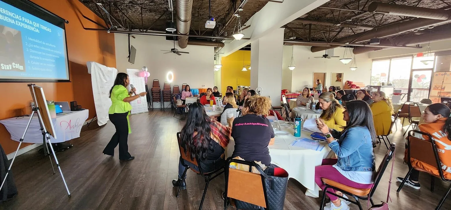 Mujeres participando en un taller con Margarita Foss, reunidas alrededor de mesas mientras ella enseña