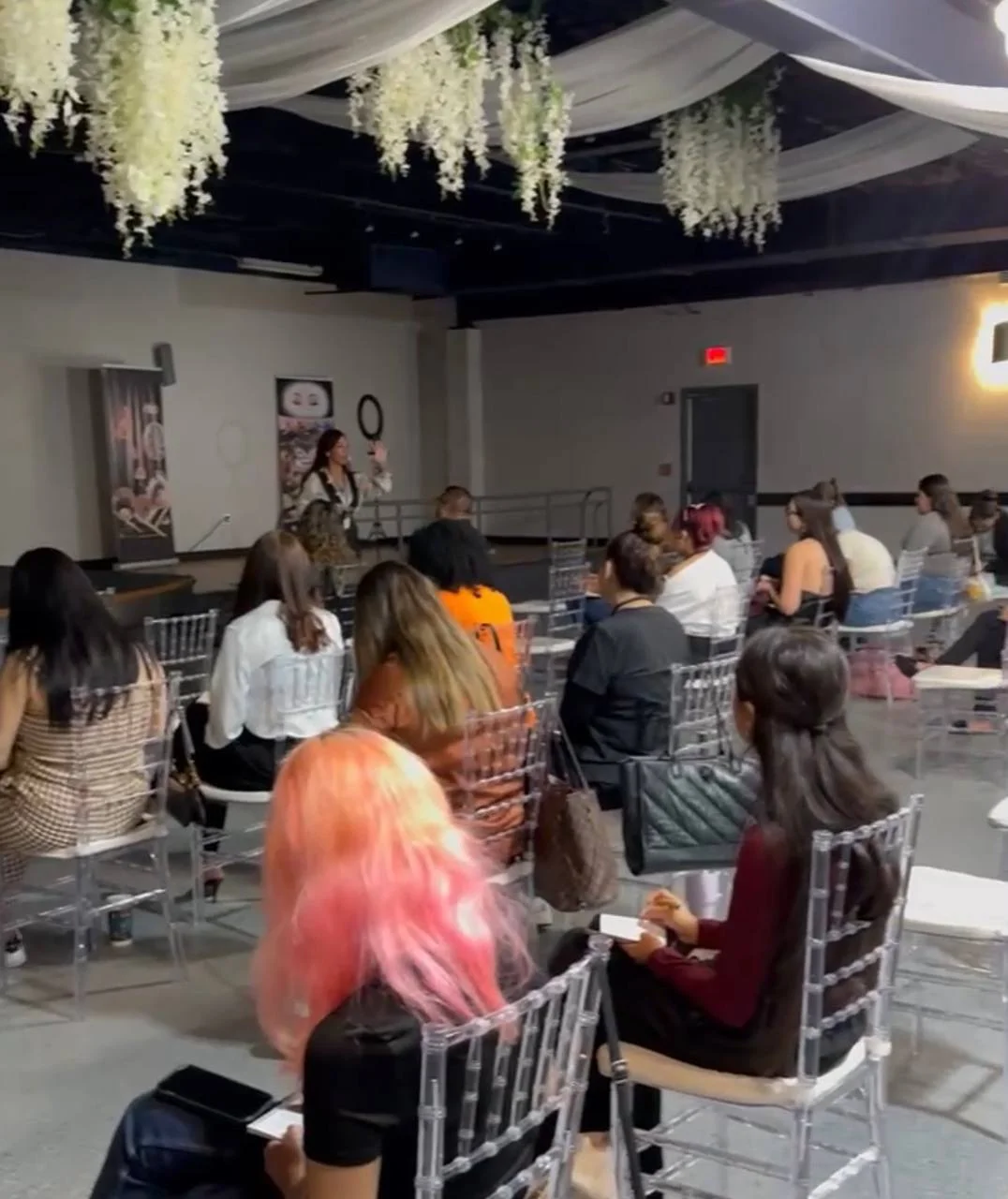 Salón de Sleeping Beauty con flores blancas colgantes y mujeres participando en un taller